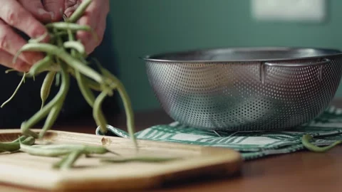Woman's hands sorting and preparing fresh green beans near a metal colander Stock Footage 343555524