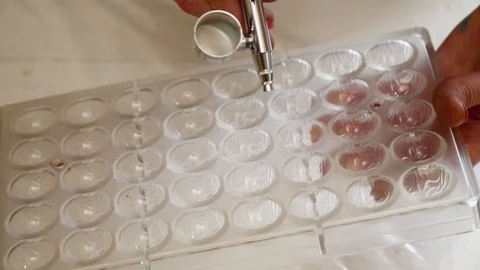 Woman's hands spraying the color to the candy forms slow motion Stock Footage 74476089