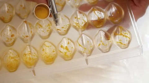 Woman's hands spraying the color to the candy forms closeup Stock Footage