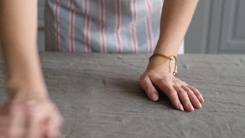 Woman's hands spread a gray tablecloth on the table to serve dinner for the Stock Footage 122992473