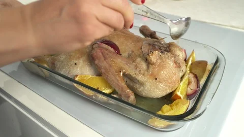 Woman's hands spread by marinade raw goose, stuffed sliced apples. Goose prepare Vídeos de archivo 99587041