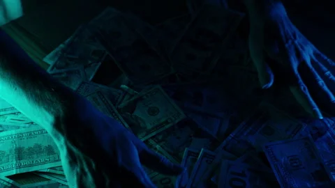 A woman's hands spread a stack of US dollar banknotes across a table under Stock Footage 296334090