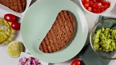 Woman's hands spreading mashed avocado on slice of healthy toasted bread Stock Footage 138379271