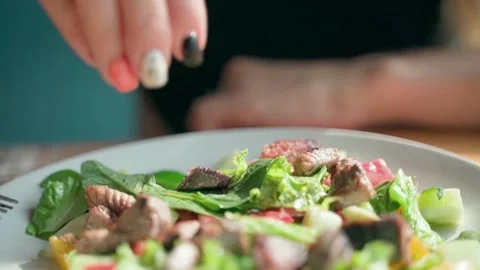 A woman's hands squeeze fresh lime on a brightly colored salad. Slow-motion. Video stock 234021996