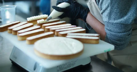 The woman's hands squeezing the cream on a cake and desserts. Tasty cream Stock Footage 134577829