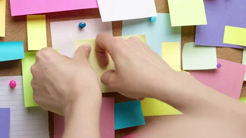 A woman's hands stick a paper note on a reminder board. Business idea concept. Stock Footage 232259894