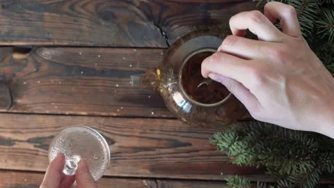 Woman's hands stir tea in a pot on a wooden table with fir branches Stock Footage 140808567