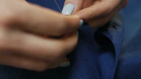 Woman's hands stitching button on a shirt in tailor shop. Close-up view. Stock Footage 152187256