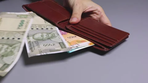 Woman's hands take out several Indian banknotes from the brown leather wallet Stock Footage 303508601