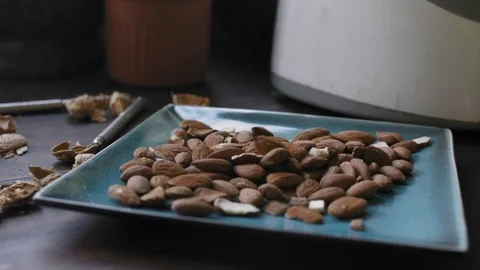 Woman's hands taking almonds from a blue plate	 Stock Footage 75759462