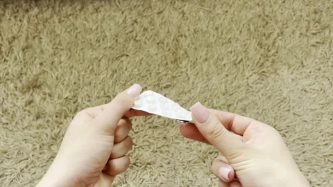 Woman's hands taking a single white pill from a blister pack for treatment... Vídeos de archivo 335141526