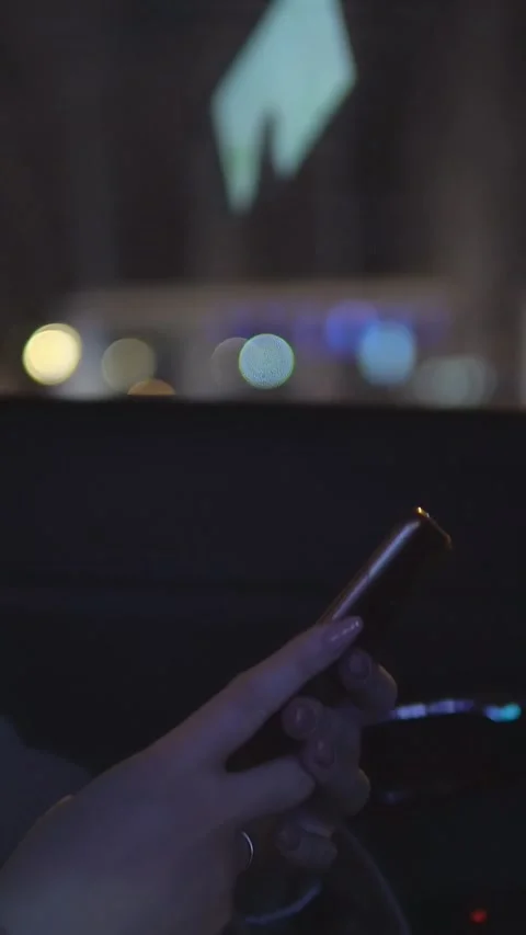 Womans hands texting on a smartphone inside a moving car at night, with Video stock 341678759