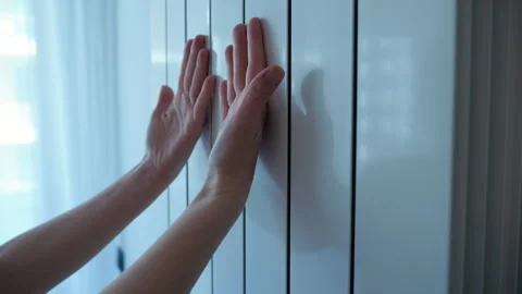 Woman's hands touching modern home radiator Stock Footage 345481218