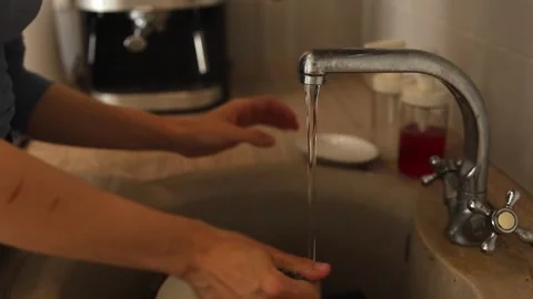 Woman's hands turning faucet knobs run water kitchen sink while washing dishes Video stock 288184417
