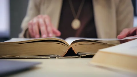Woman's hands turning the pages of a large old book while studying Stock Footage 336042162