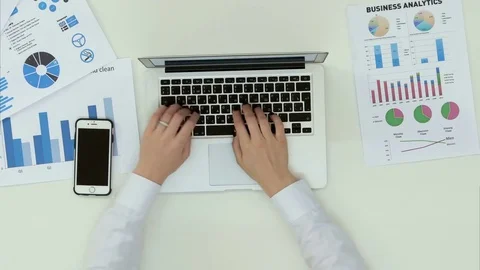 Woman's hands typing on laptop computer at office desk with statistics graph Stock Footage 71615031