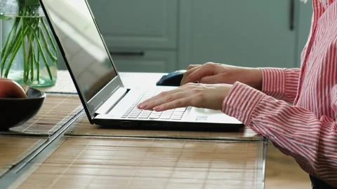 Woman's hands typing on a laptop keyboard while working remotely from a home Stock Footage 340231708