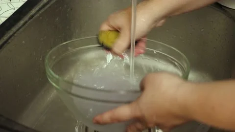 A woman's hands under running water from the faucet with washing a glass cup Stock Footage 196816652