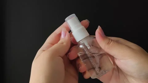 A womans hands unscrew or twist the spray bottle cap on a black background Vídeo Stock 314975443