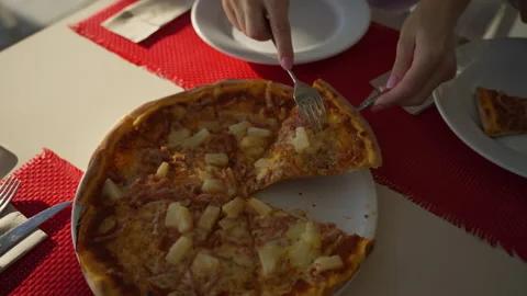 Woman's hands use knife and fork to cut slice of fresh hawaiian pizza with .. Stock Footage 321021572