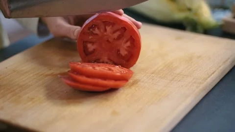 Woman's hands using kitchen knife cutting fresh tomato on wooden cutting board Stock Footage 133346663