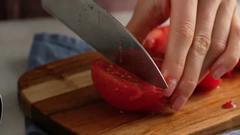 Woman's hands using kitchen knife cutting fresh tomato on wooden cutting board Stock Footage 138094322