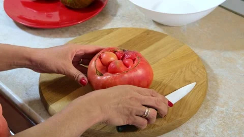 Woman's hands using kitchen knife cutting clumsy, ugly, juicy tomato Stockbeeldmateriaal 138771758