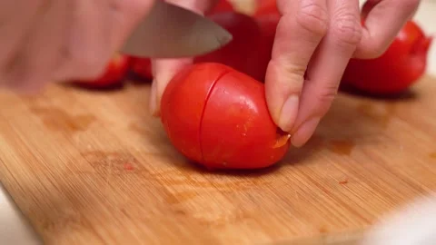 Woman's hands using kitchen knife cutting fresh tomato on wooden cutting board. Vidéo 142216408
