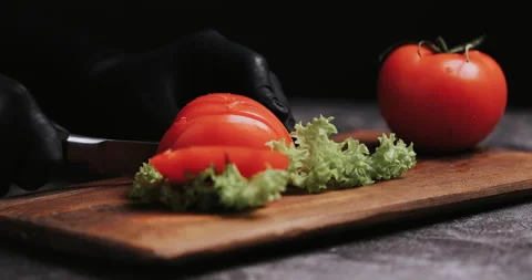 Woman's hands using kitchen knife cutting fresh tomato on wooden cutting board.  Video stock 148244941