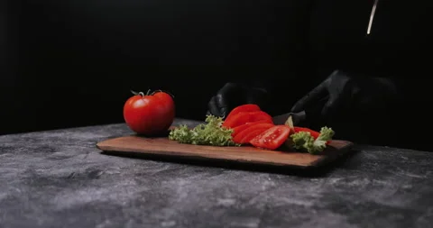 Woman's hands using kitchen knife cutting fresh tomato on wooden cutting board.  Stock Footage 148245161