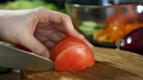 Woman's hands using kitchen knife cutting fresh tomato on wooden cutting board Stock Footage 149871767