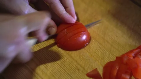 Woman's hands using kitchen knife cutting fresh tomato on wooden cutting board Stock Footage 154633104