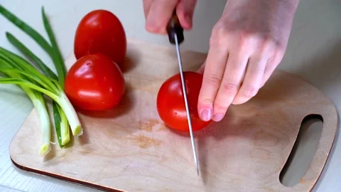 Woman's hands using kitchen knife cutting fresh tomato on wooden cutting board Video stock 155646296
