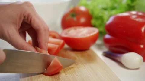 Woman's hands using kitchen knife cutting fresh tomato on wooden cutting board Video stock 157356645