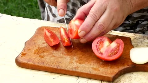 Woman's hands using kitchen knife cutting fresh tomato on wooden cutting board. Stock Footage 246078951