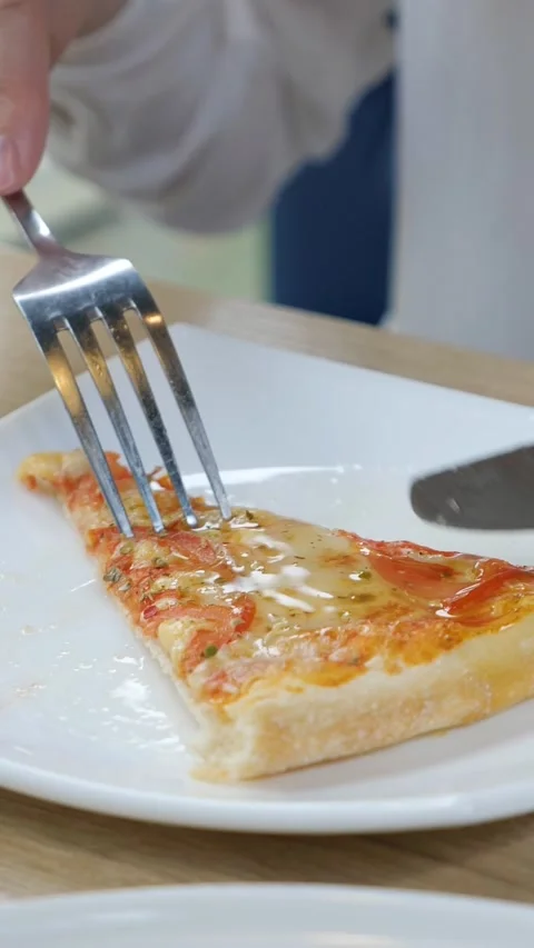 Womans hands using a knife and fork to cut a delicious slice of margherita pizza Stock Footage 341678385