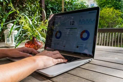 Woman's hands using laptop with analytical graph on desk in the garden Stock Photos