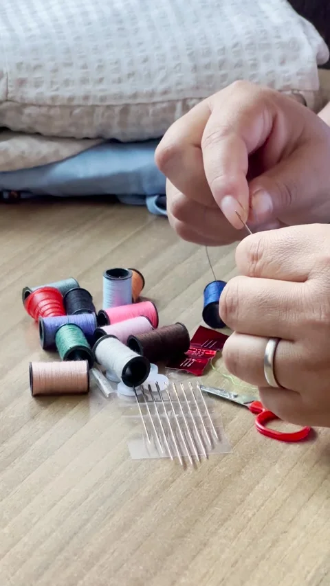 Woman's hands using a needle and thread to sew in close up 库存影片 347792450