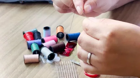 Woman's hands using a needle and thread to sew in close-up Stock Footage 347792471