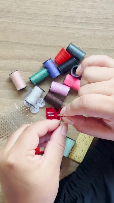 Woman's hands using a needle and thread to sew in an overhead view 库存影片 347792478