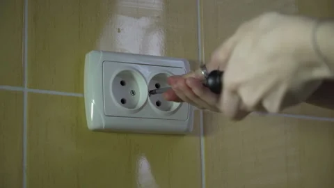 Woman's hands using a screwdriver when installing a new electrical outlet Stock Footage 260499066