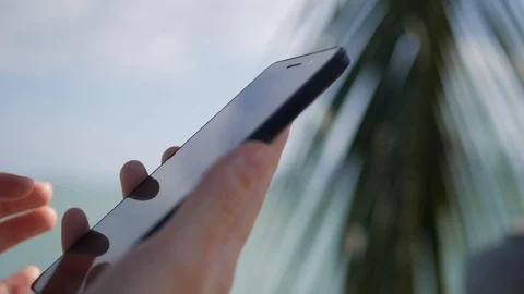 Womans hands using smartphone over background sea and palm trees. Girl touching Video stock 87240875