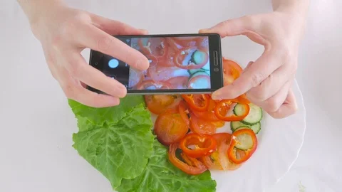 Woman's hands using a smartphone take pictures of fresh vegetable salad on a Stock Footage 99839576