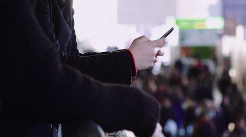 Woman's hands using smartphone to text a message with crowd in background Stock Footage 49816423