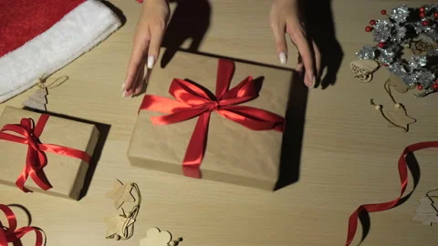 Woman's hands wrapping and rotating Christmas gifts at home, view from above Stock Footage 166120933