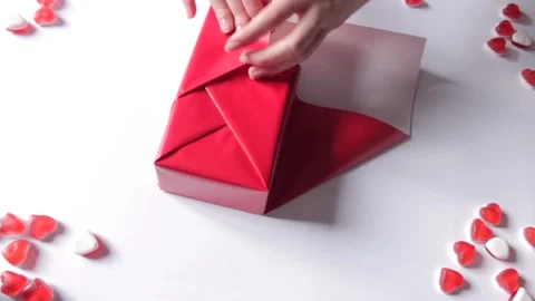 Woman's hands wrapping gift box in a red paper, uses modern design. Preparation Stock Footage 231309519