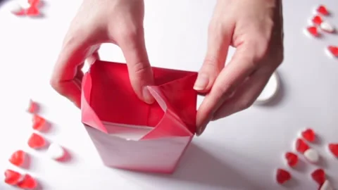 Woman's hands wrapping gift box in a red paper, uses modern design. Preparation Stock Footage 231370404