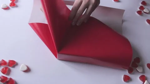 Woman's hands wrapping gift box in a red paper, uses modern design. Preparation Stock Footage 231370448