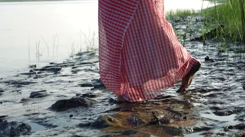 A woman's leg in a saree ,walking  through mud into the river . Stock Footage 252919344
