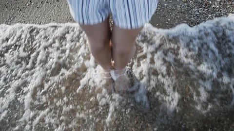 Woman's legs makes small jumps in the sea water at sunset. Close-up, female l 스톡 동영상 115029945